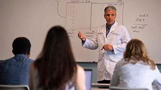 Group of doctors in white lab coats reviewing information on a whiteboard.